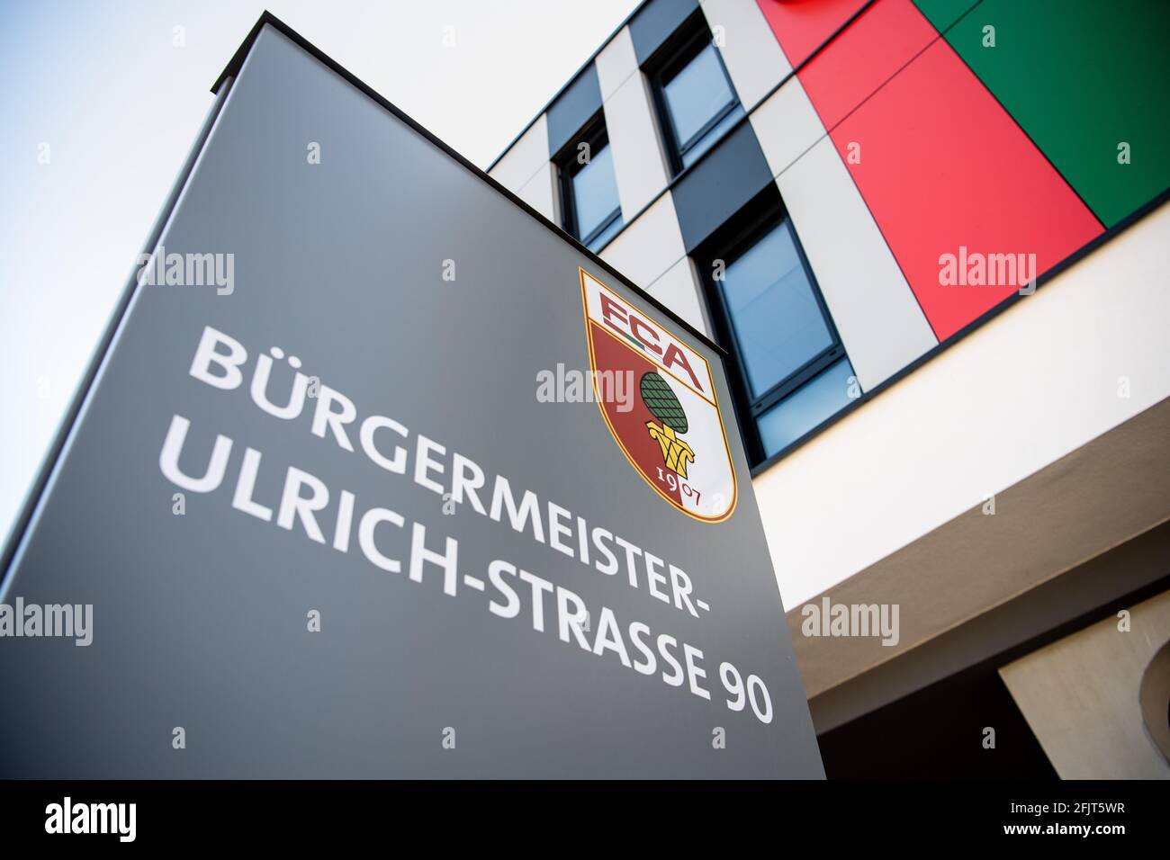 Augsburg, Deutschland. April 2021. Das Vereinslogo des FC Augsburg, ein  Wappen mit der Aufschrift FCA und das Bild einer Pinienmutter, ist auf  einer Säule vor den Büros des FC Augsburg in der