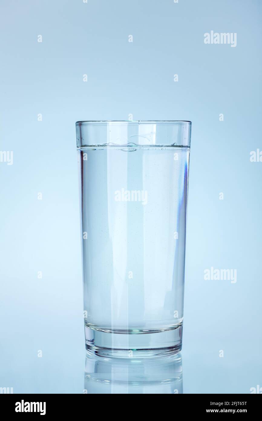 Klares Glas Becher mit Wasser mit einer Reflexion auf einem kalten blauen  Hintergrund gefüllt ein Wasser Utensil Element, niemand Stockfotografie -  Alamy