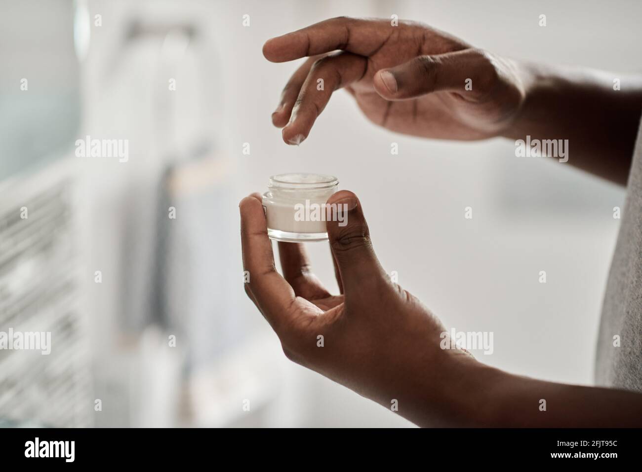 Afrikanischer Mann, der mit ihm Creme aus einem Glas nahm Finger Stockfoto