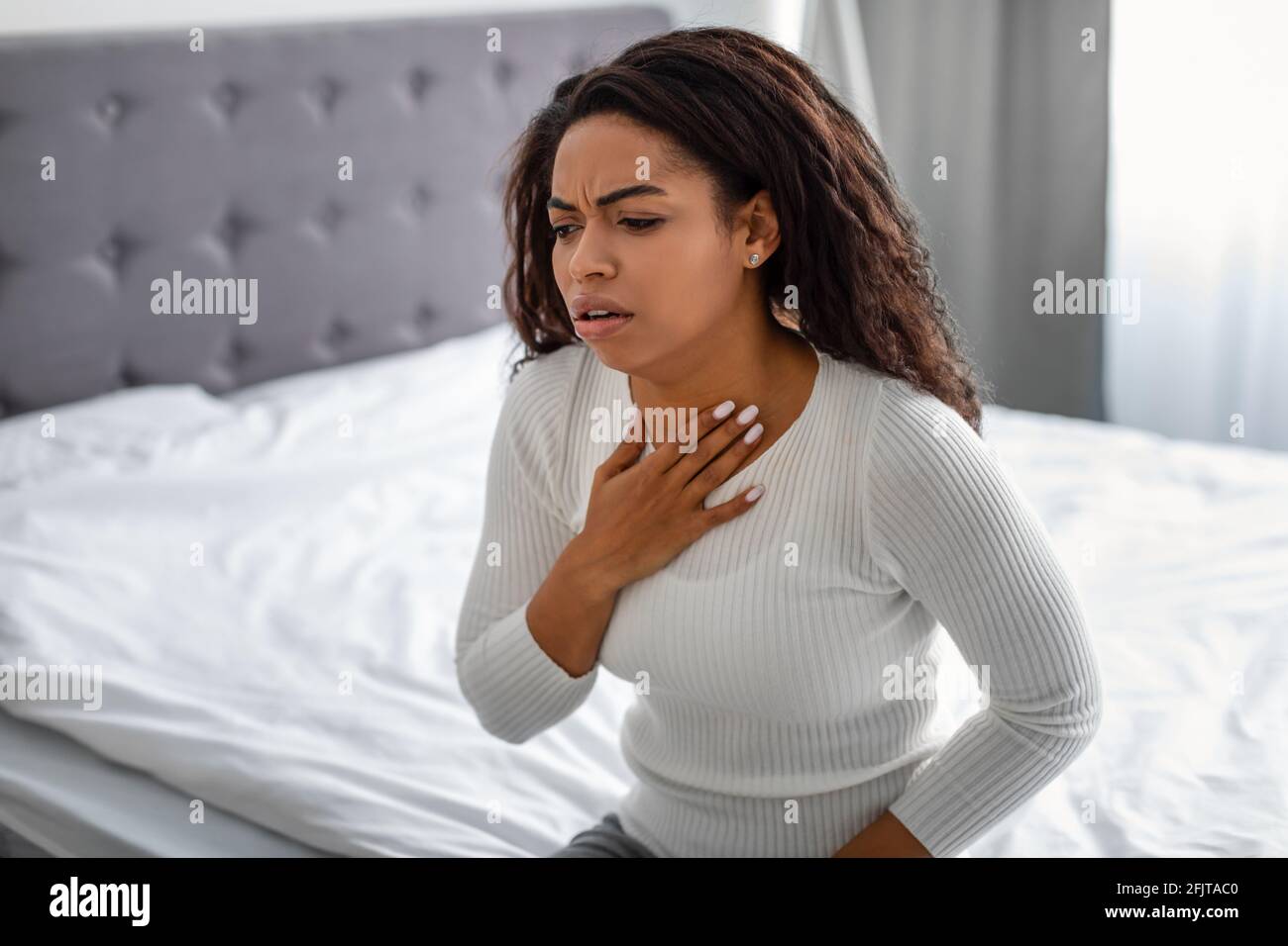 Junge schwarze Frau hustet, leidet an Halsschmerzen Stockfoto