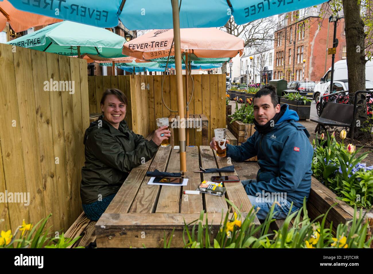 North Berwick, East Lothian, Schottland, Großbritannien, 26. April. Unternehmen wieder geöffnet: Mit Lockdown-Beschränkungen heute gelockert, Pubs mit Sitzgelegenheiten im Freien können Kunden bedienen. Ein Paar aus Edinburgh genießt trotz des kühlen Wetters im Ship Inn ein erstes Bier im Freien. Stockfoto