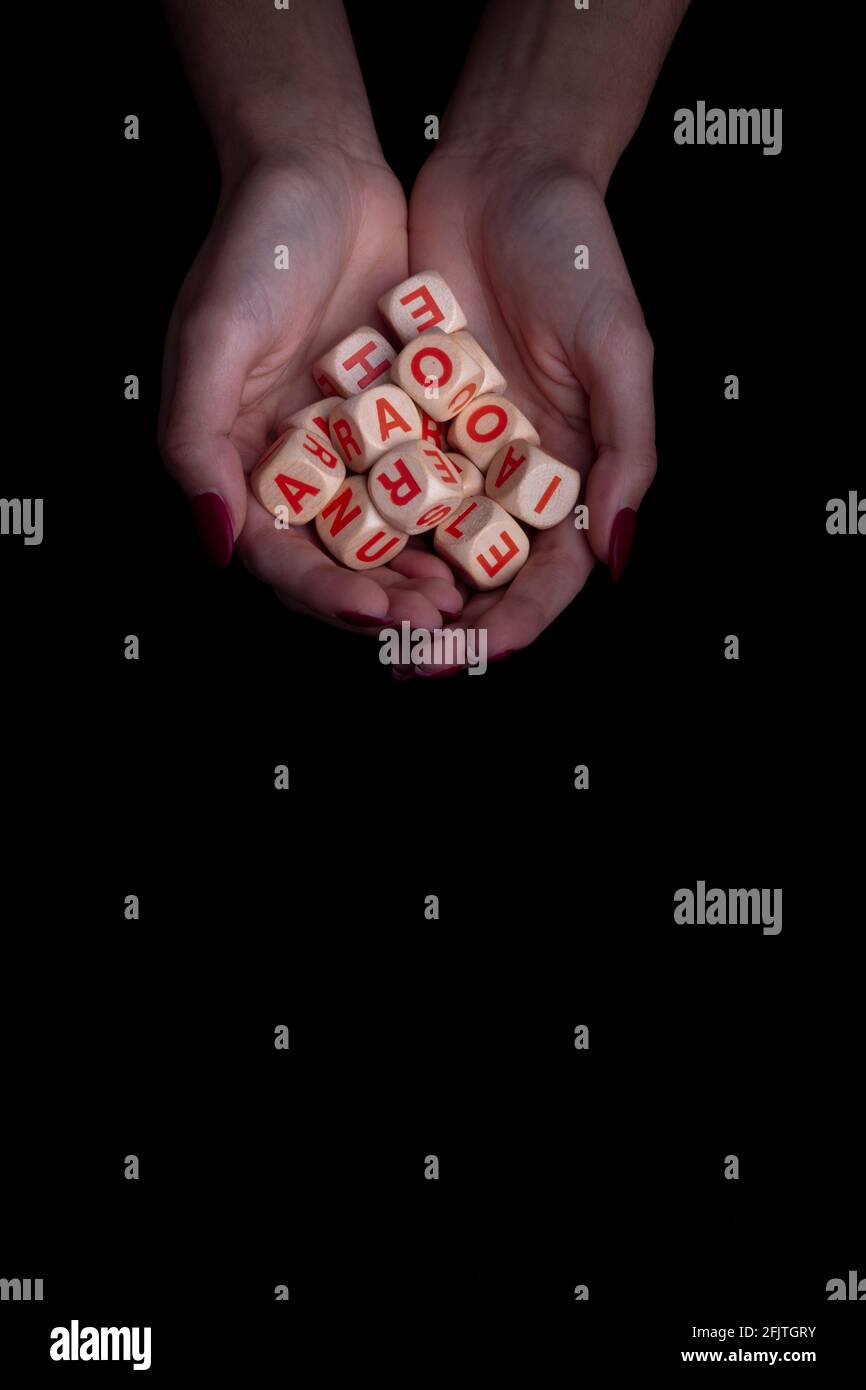 Weibliche Hände mit Alphabet-Spielzeugdices auf schwarzem Hintergrund und Kopierraum. Dyslexya-Konzept Stockfoto