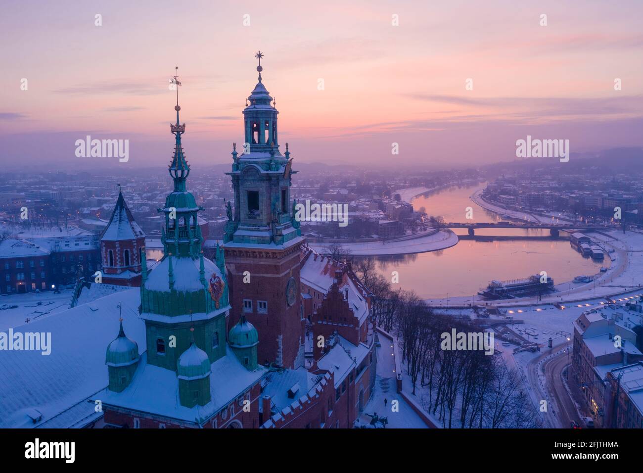 Wawel Royal Castle im Winter. Schnee auf den Dächern und Türmen der Kathedrale des Wawel-Schlosses und der Weichsel im Zentrum von Krakau-Polen bei Sonnenuntergang. Stockfoto