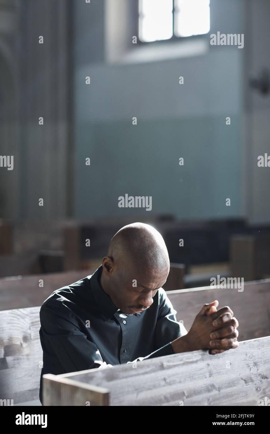 Afrikanischer Mann, der in der Kirche sitzt und betet Stockfoto