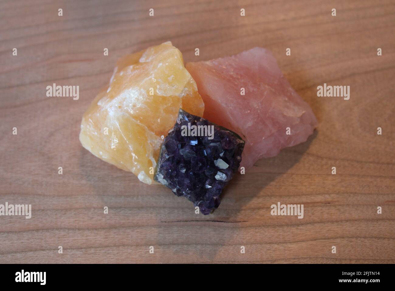 Ein Trio aus Rosenquarz, goldenen Calcit- und Amethyst-Steinen Stockfoto