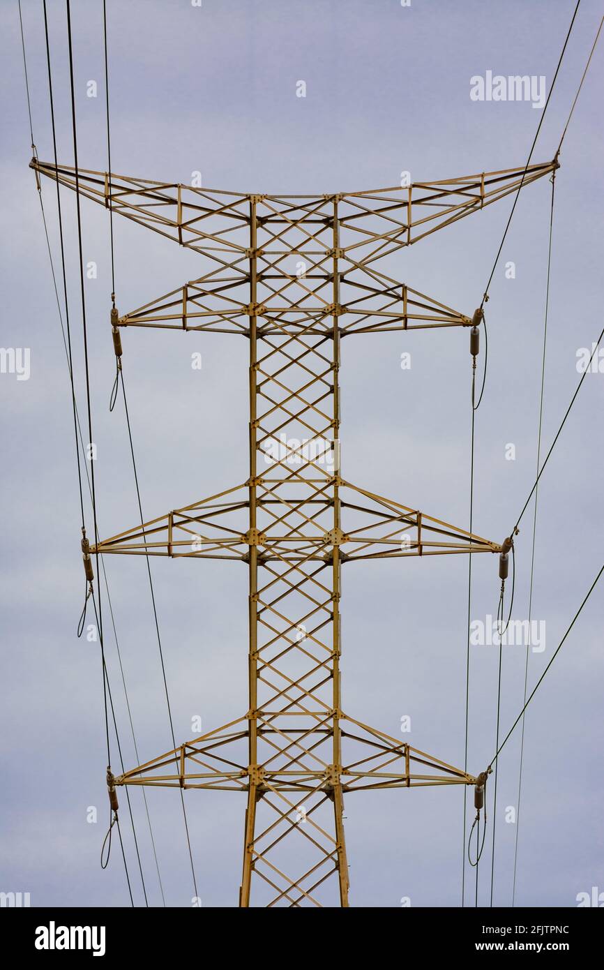 Symmetrische Erfassung der Oberseite des Hochspannungsmastes mit klarem Himmel im Hintergrund Stockfoto