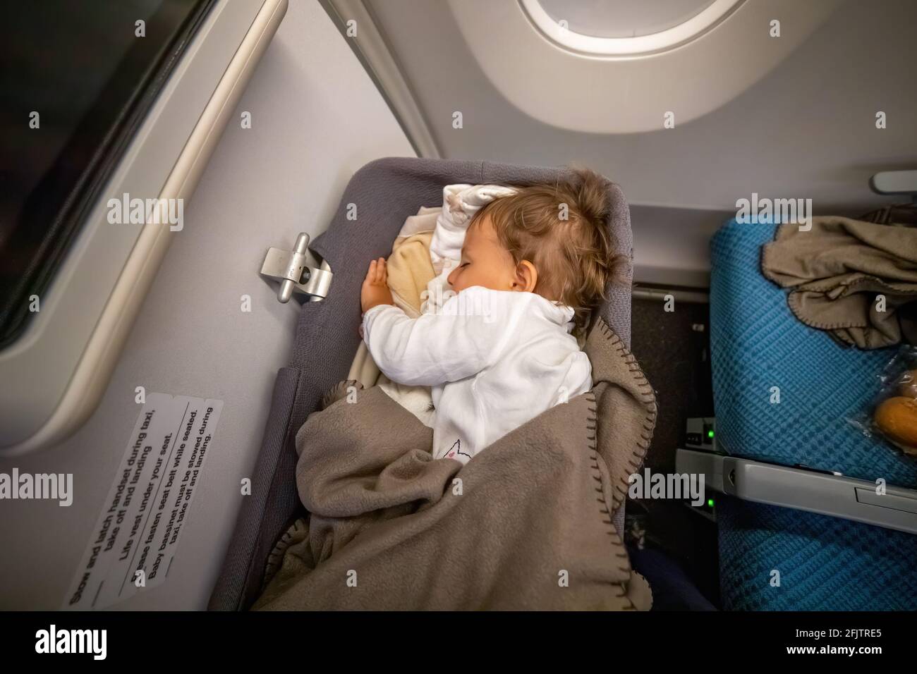 Der Kleinkinder schläft sicher und bequem im Baby Bussinet auf einem langen Flug Stockfoto