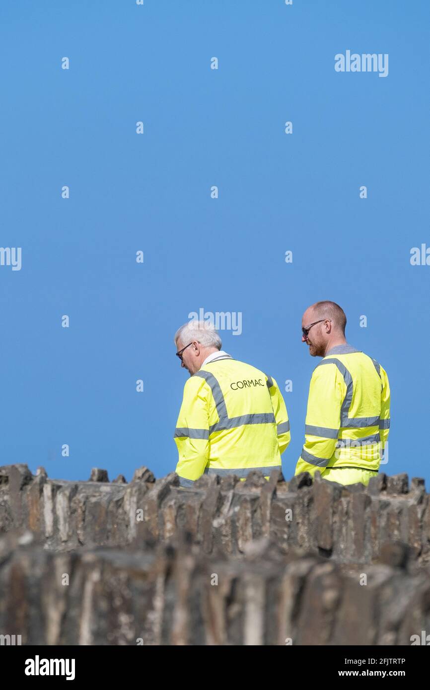 Zwei Cormac-Arbeiter tragen fluureszend gelbe Hi-viz-Sicherheitsjacken, die vor einem strahlend blauen Himmel gesehen werden. Stockfoto