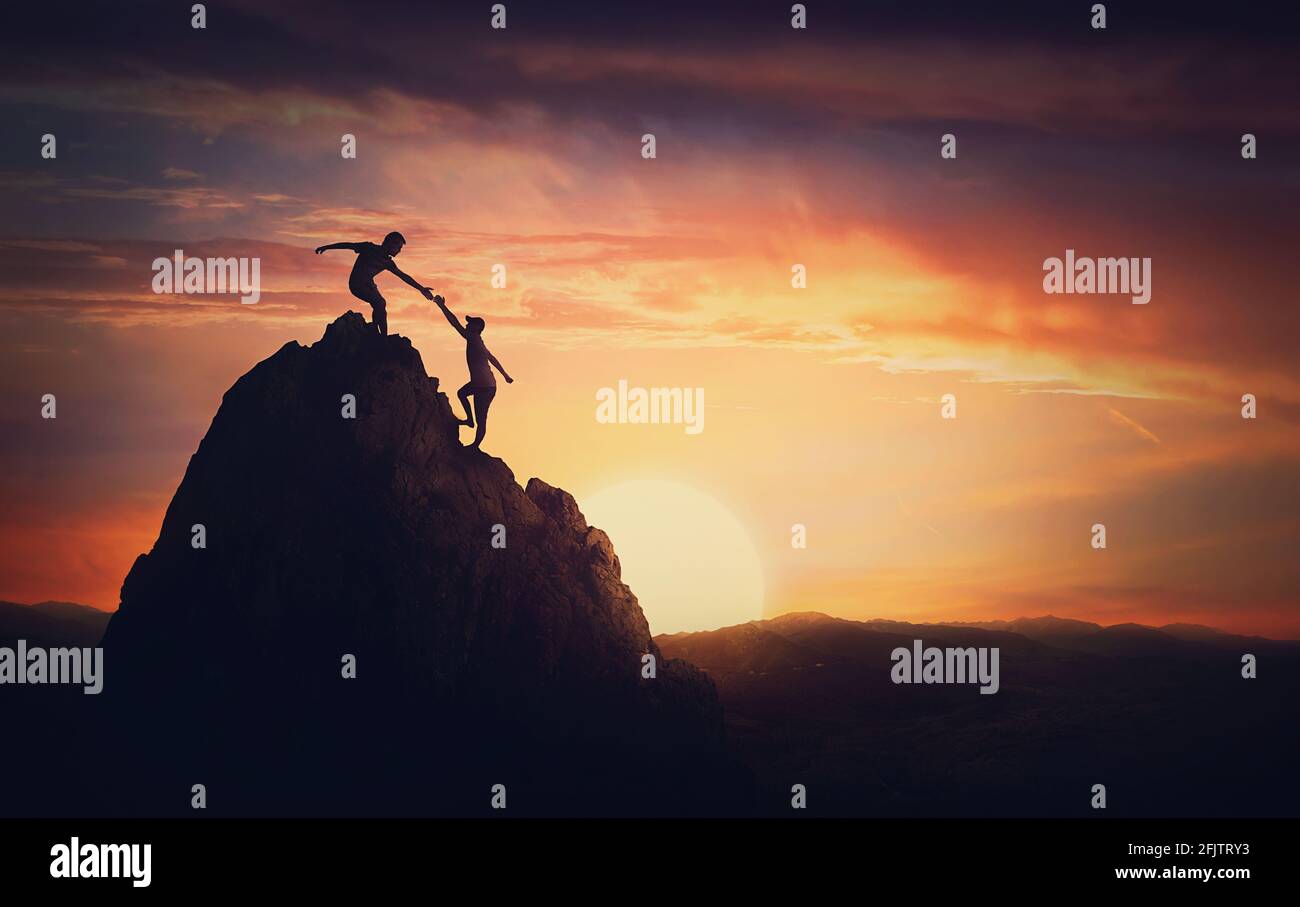 Blick auf die Landschaft mit einem Team von zwei Bergsteigern auf der Spitze des Berges. Person, die einem anderen hilft, Hindernisse zu überwinden und gemeinsam die Spitze zu erreichen. Teamarbeit Stockfoto