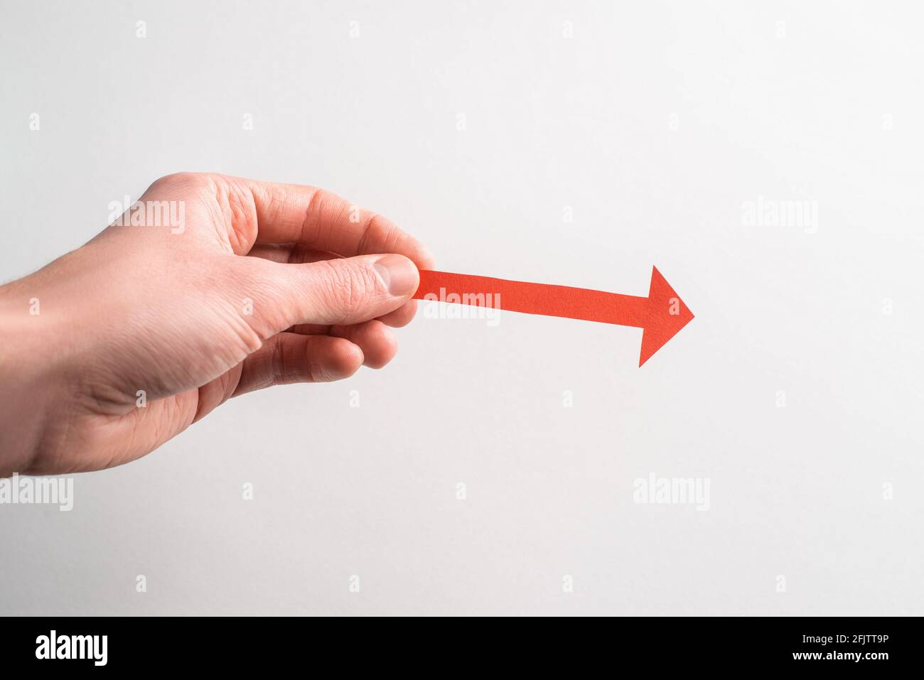 Hand mit einem roten Papierpfeil, der nach rechts zeigt Stockfoto