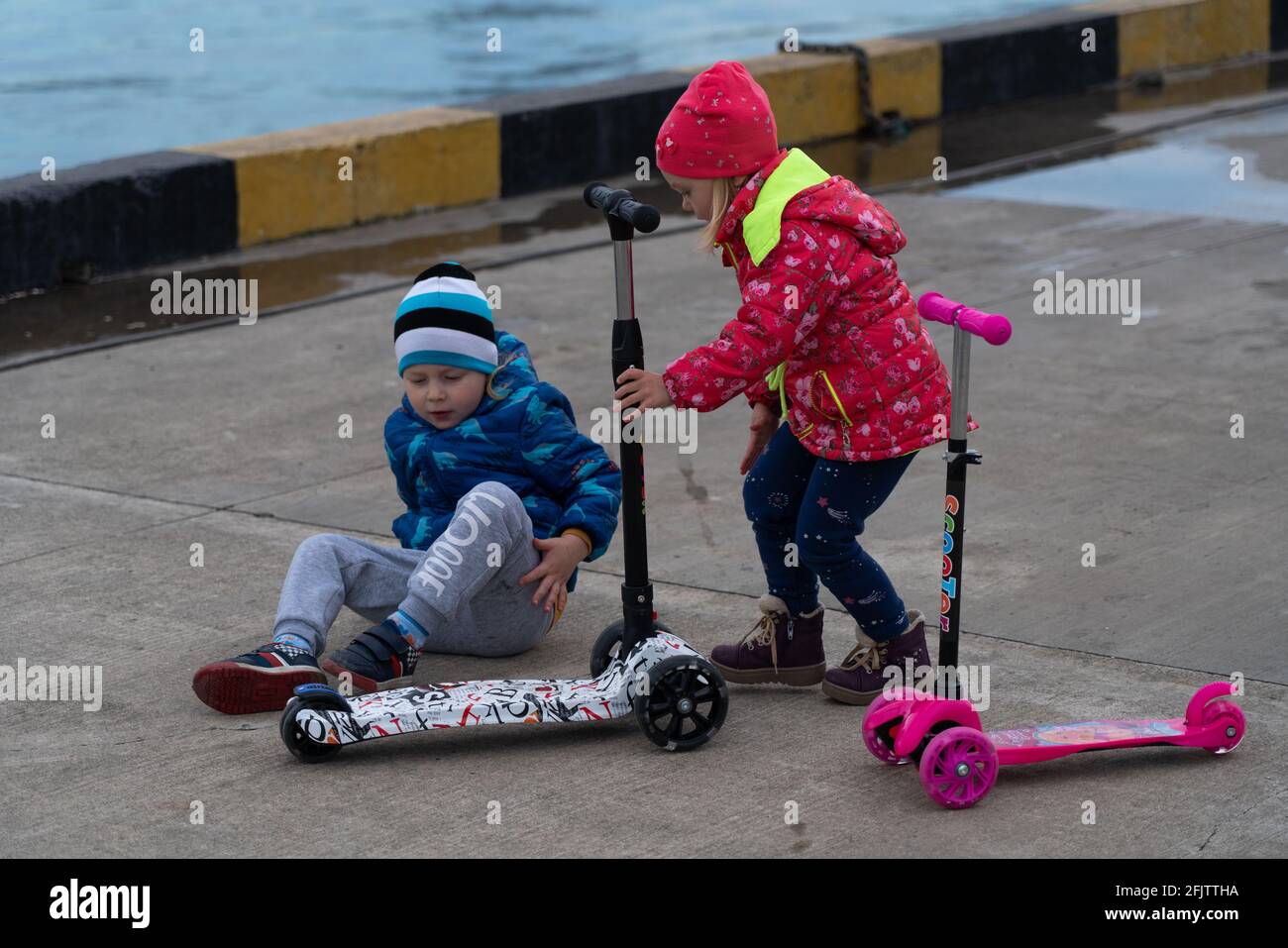 Kinder fahren Roller im Hafen Stockfoto