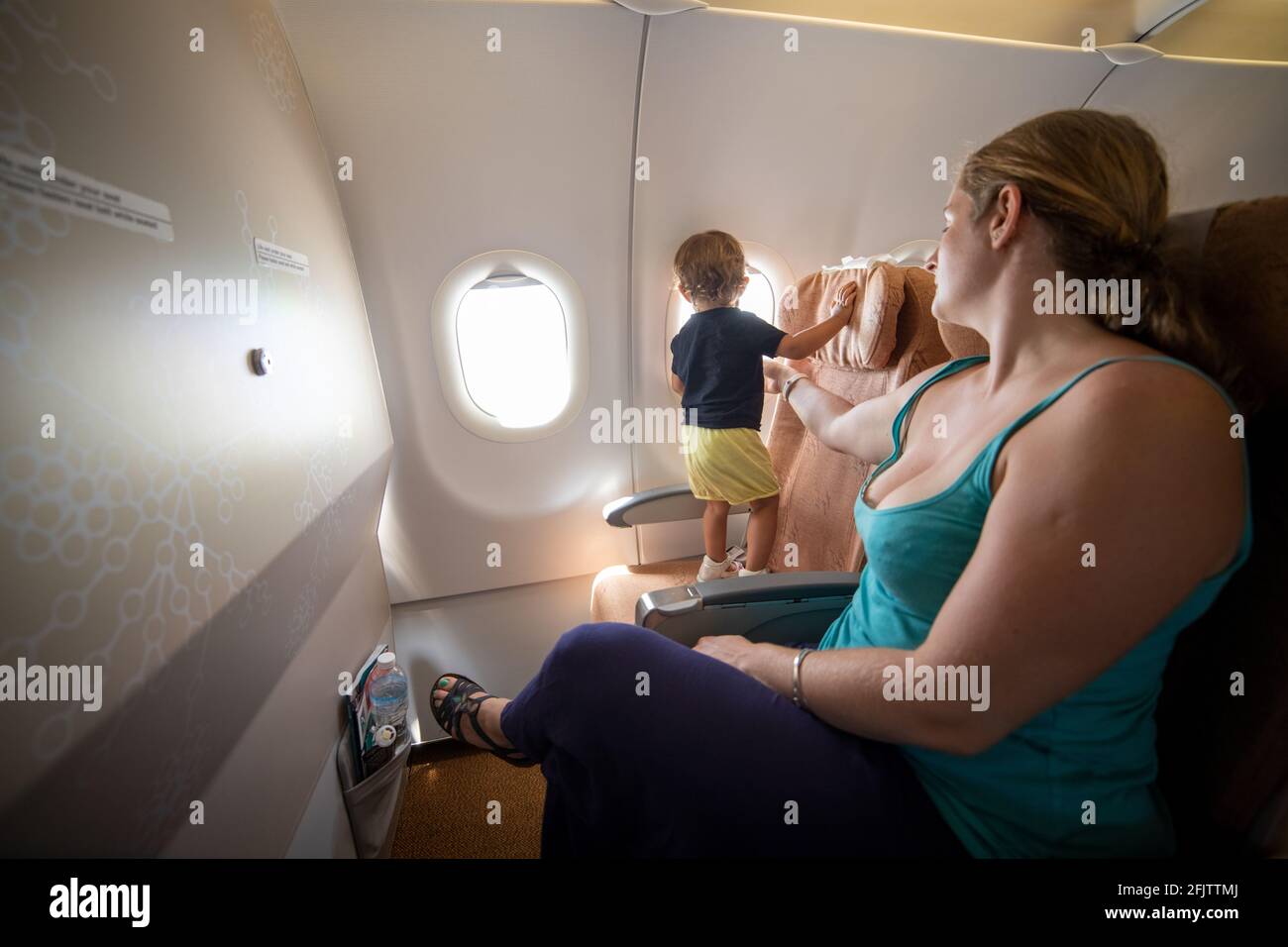 Mama hält ein kleines Kleinkind mit der Hand im Flugzeug. Gefährlich. Stockfoto
