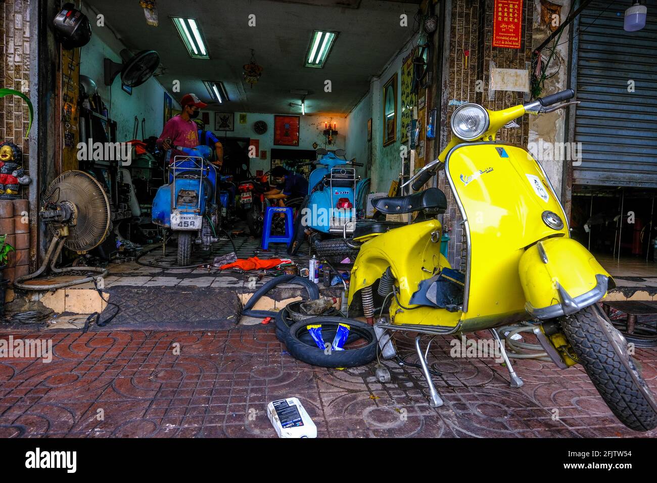 Ein Vespa-Roller wird vor einer kleinen Vespa-Reparaturwerkstatt in Chinatown in Bangkok, Thailand, repariert Stockfoto