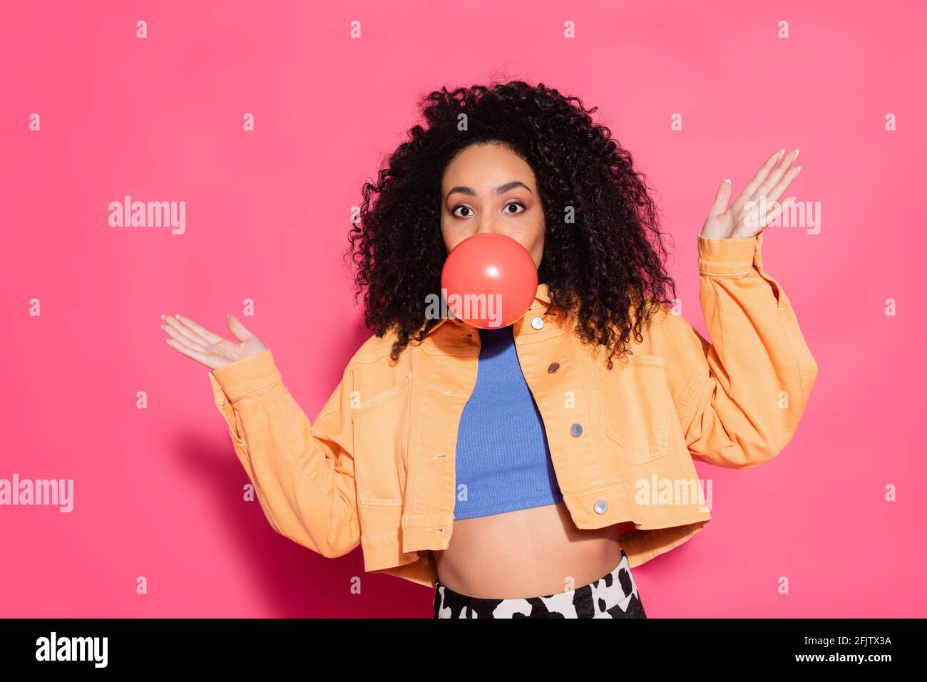 Verwirrte afroamerikanische Frau bläst Kaugummi auf rosa Stockfoto