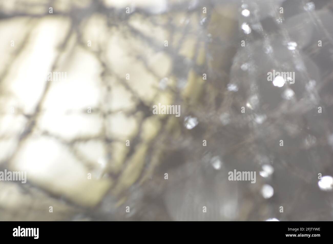 Nahaufnahme einer verschwommenen silbernen Wellenfäden auf einem unscharfen Hintergrund mit abstrakten Bokeh-Lichtern Stockfoto