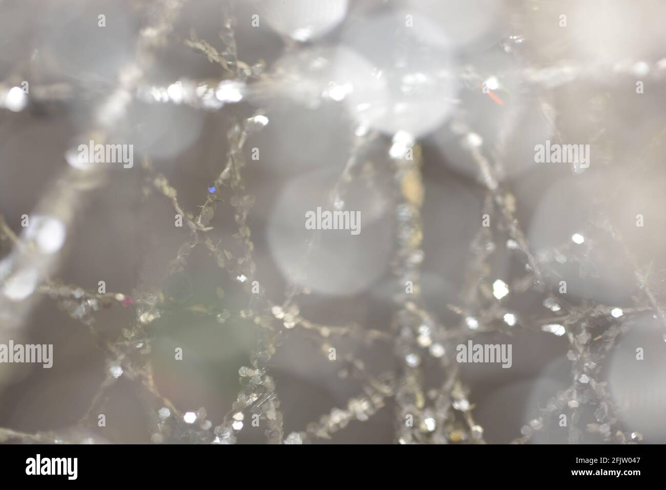 Nahaufnahme einer verschwommenen silbernen Wellenfäden auf einem unscharfen Hintergrund mit abstrakten Bokeh-Lichtern Stockfoto