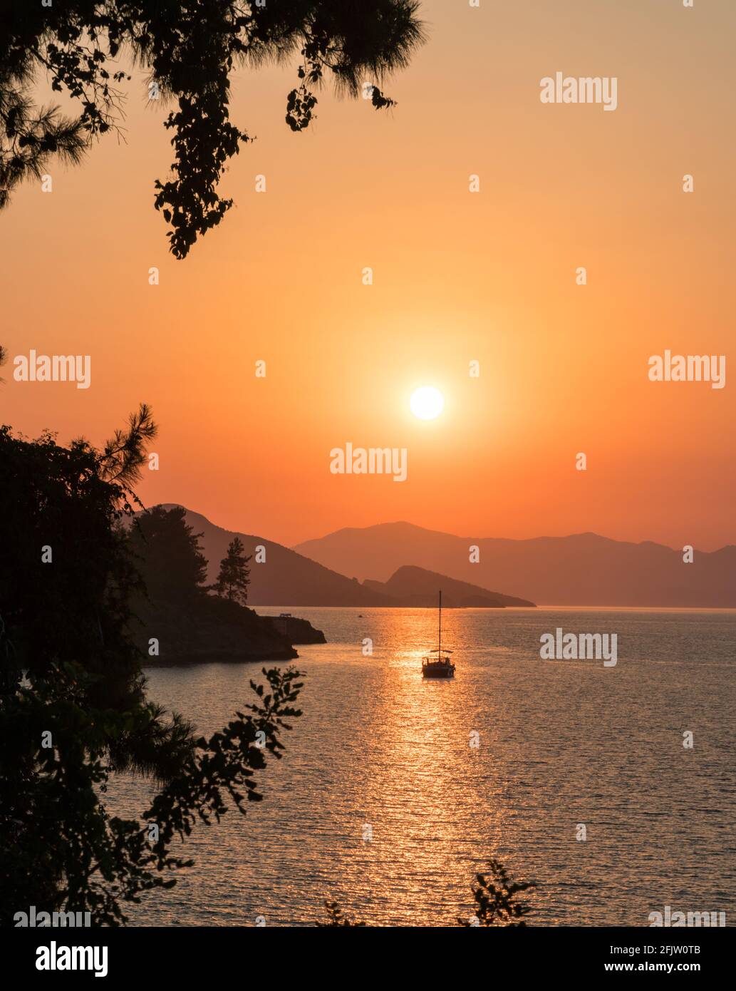Ruhiges Meer und Sonnenuntergang. Die Sonne geht hinter den Hügeln im Horizont unter. Schöne Natur Hintergrund. Stockfoto
