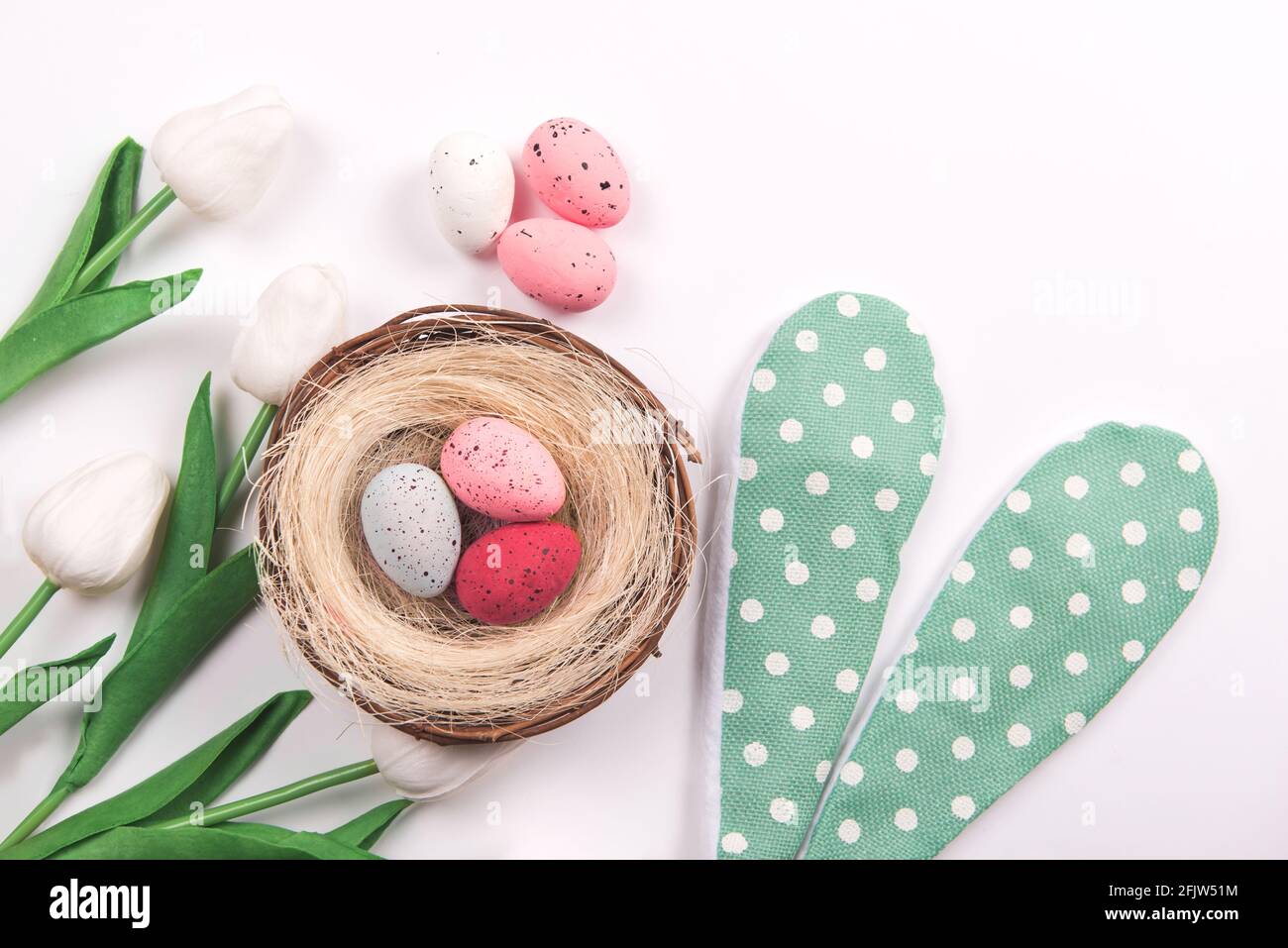 Bunte Dekorationen mit Ostereiernest mit Frühlingsblumen auf weißem Hintergrund. Copy Space, Draufsicht Stockfoto