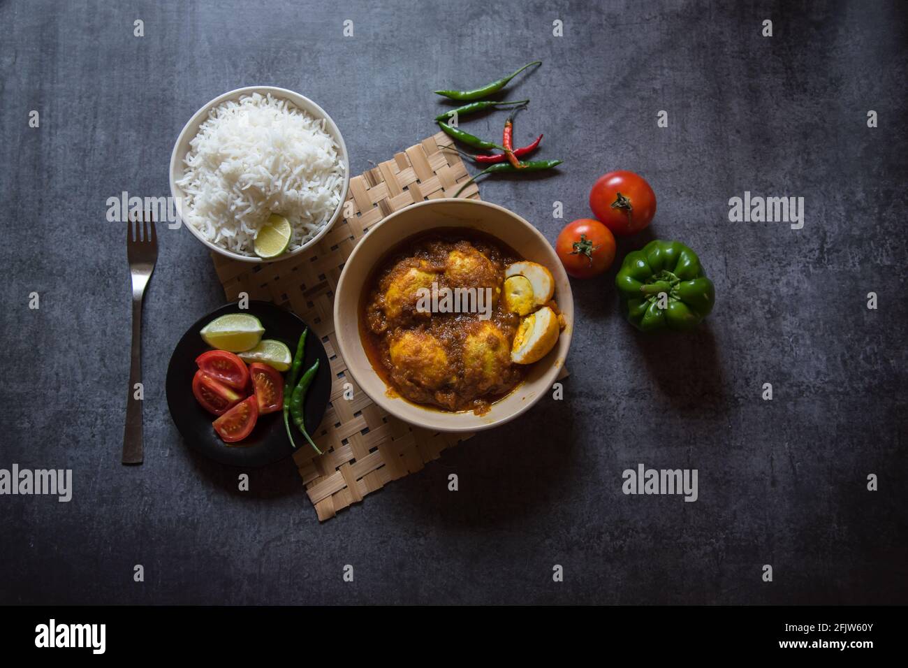 Beliebte indische Mittagsinhaltsstoffe Eiercrause in einer Schüssel zusammen mit Reis- und Salatwürzen. Draufsicht, selektiver Fokus. Stockfoto