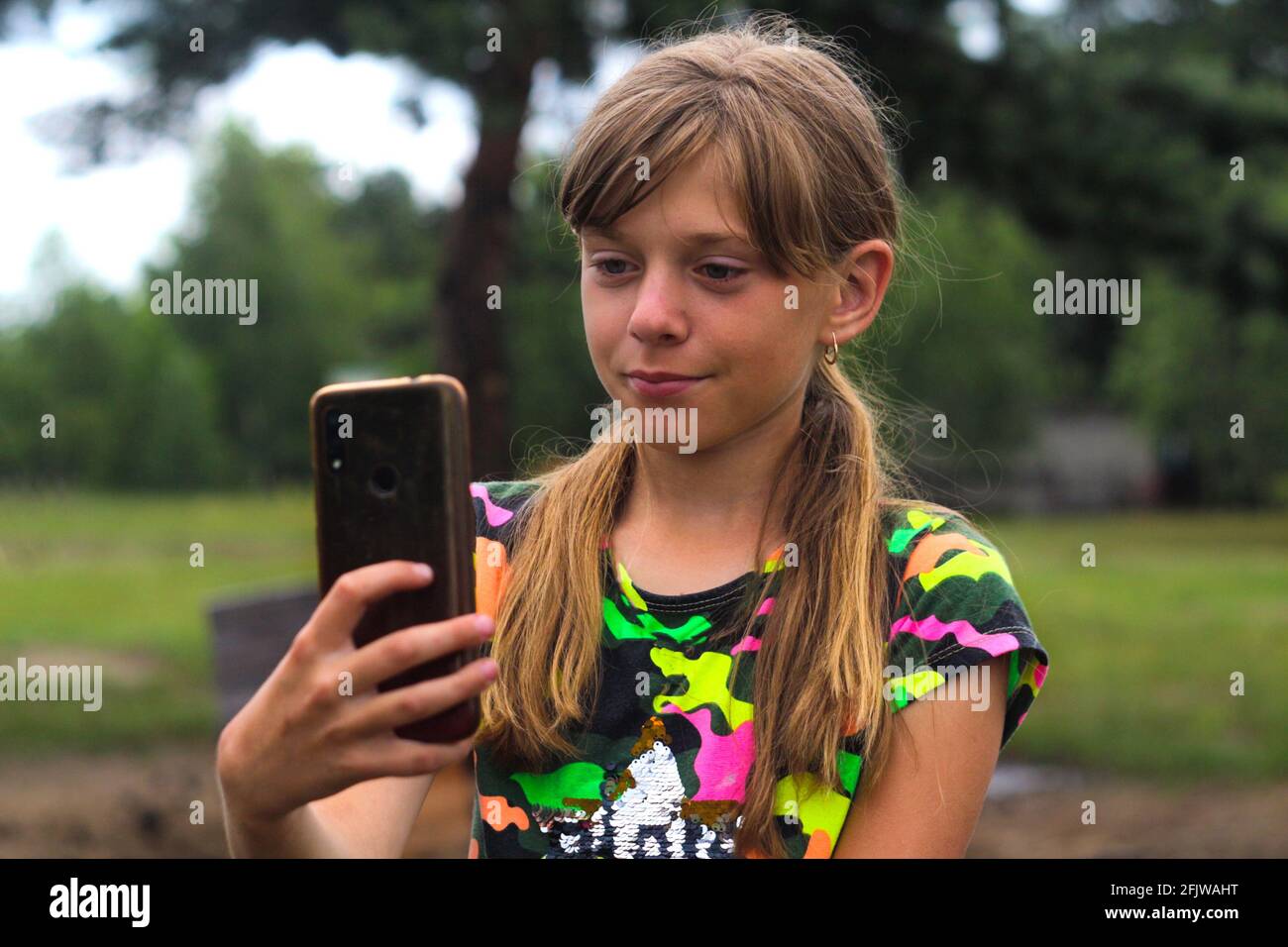 Unschärfe zehn Jahre altes Mädchen finden etwas auf dem Smartphone. Schöne  Teenager-Mädchen nimmt Selfie, während allein auf dem Park stehen. Blogging  und Live-Streaming Stockfotografie - Alamy