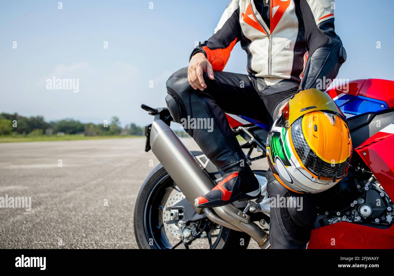 Fahrer Motorrad hält seinen Motorradhelm sitzen auf einem großen Fahren Sie auf der Straße mit weichem Fokus und über Licht Im Hintergrund Stockfoto