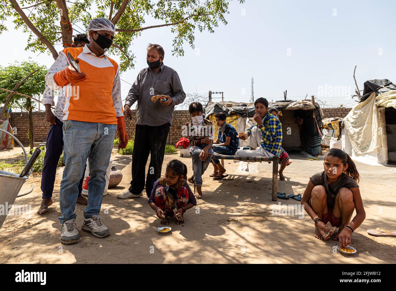 Migranten warten in Schlangen, um während der Sperre von Covid 19 von den Freiwilligen Lebensmittel zu erhalten, die verteilt werden. Stockfoto