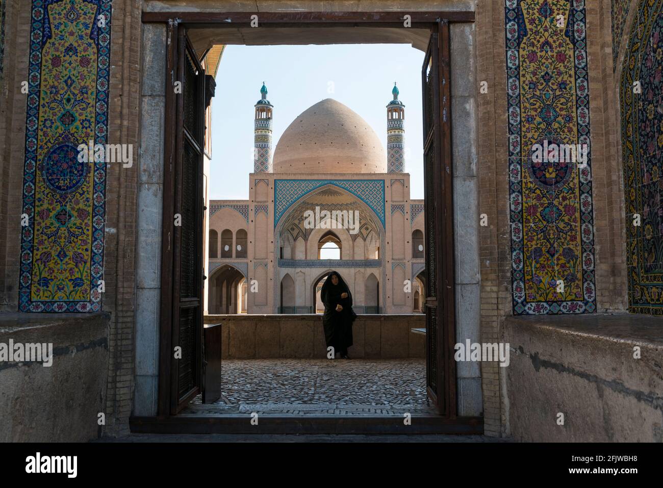 Blick in eine Moschee neben dem Großen Basar von Kashan mit einer Frau in schwarzem Tschador. Iran. Stockfoto