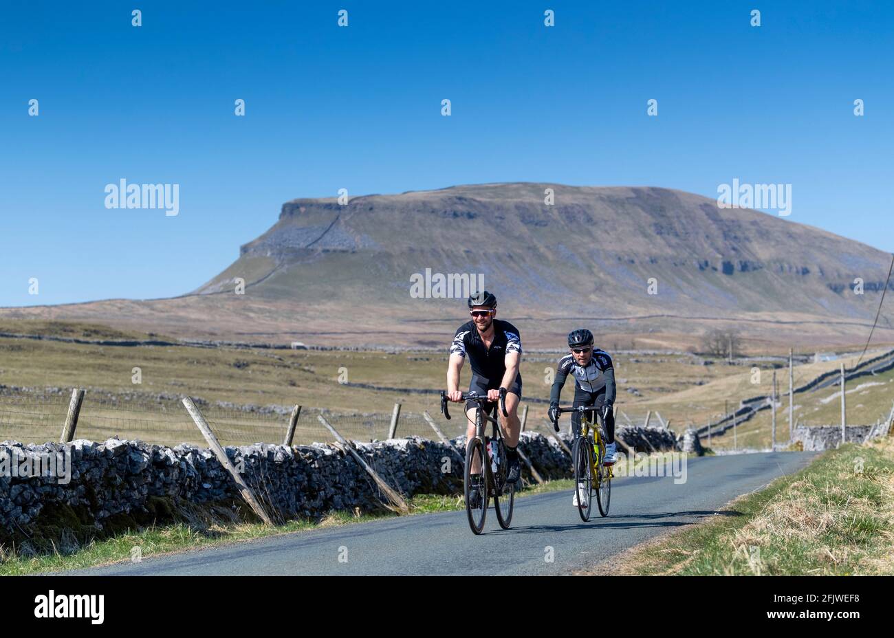 Zwei Radfahrer auf einer einspurigen Straße in der Nähe von Penyghent fielen im Yorkshire Dales National Park, Großbritannien. Stockfoto