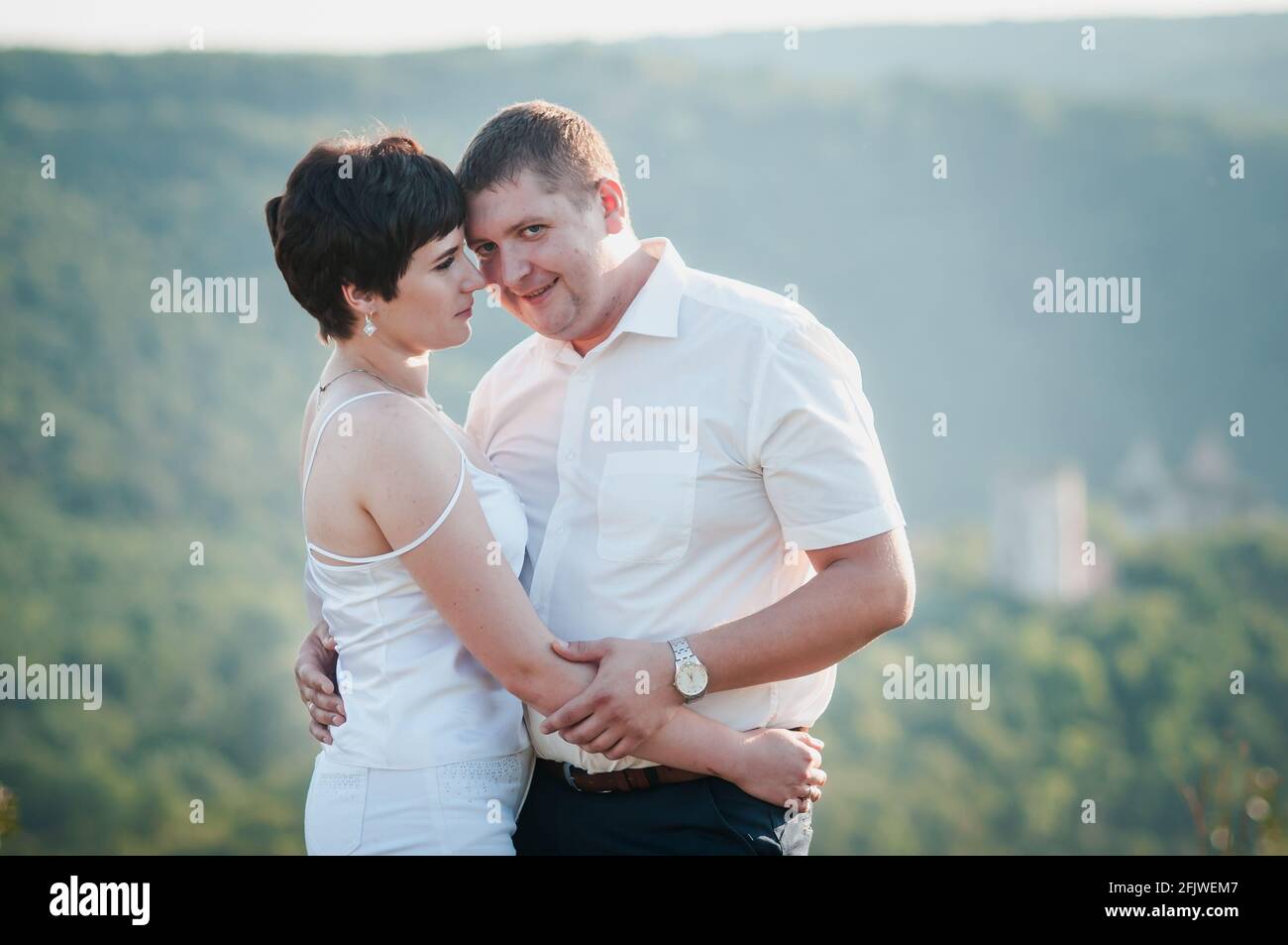Brautpaar umarmen und küssen sich auf dem Hintergrund des Waldes Stockfoto