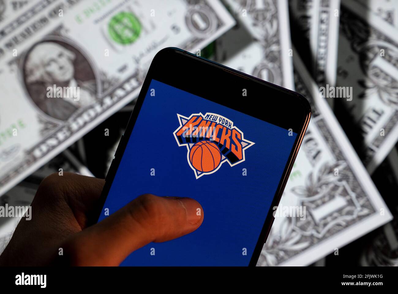 In dieser Abbildung zeigt das amerikanische Profi-Basketball-NBA-Team das New York Knicks Team-Logo auf einem Smartphone mit US-Dollar (USD) Währung im Hintergrund. Stockfoto