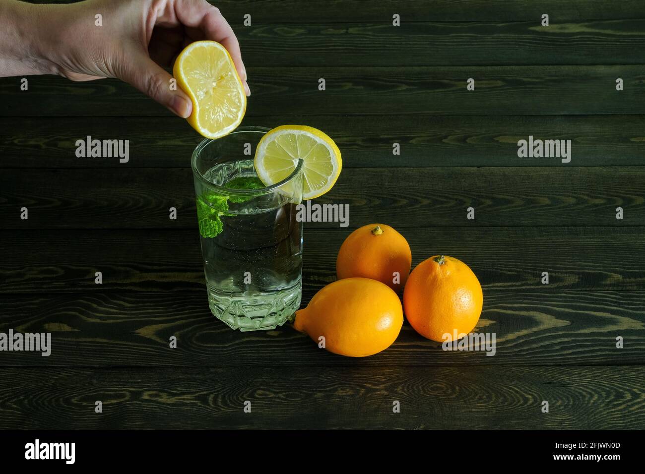 In einem Glas mit Zitronen- und Minzblättern gießen Stockfoto