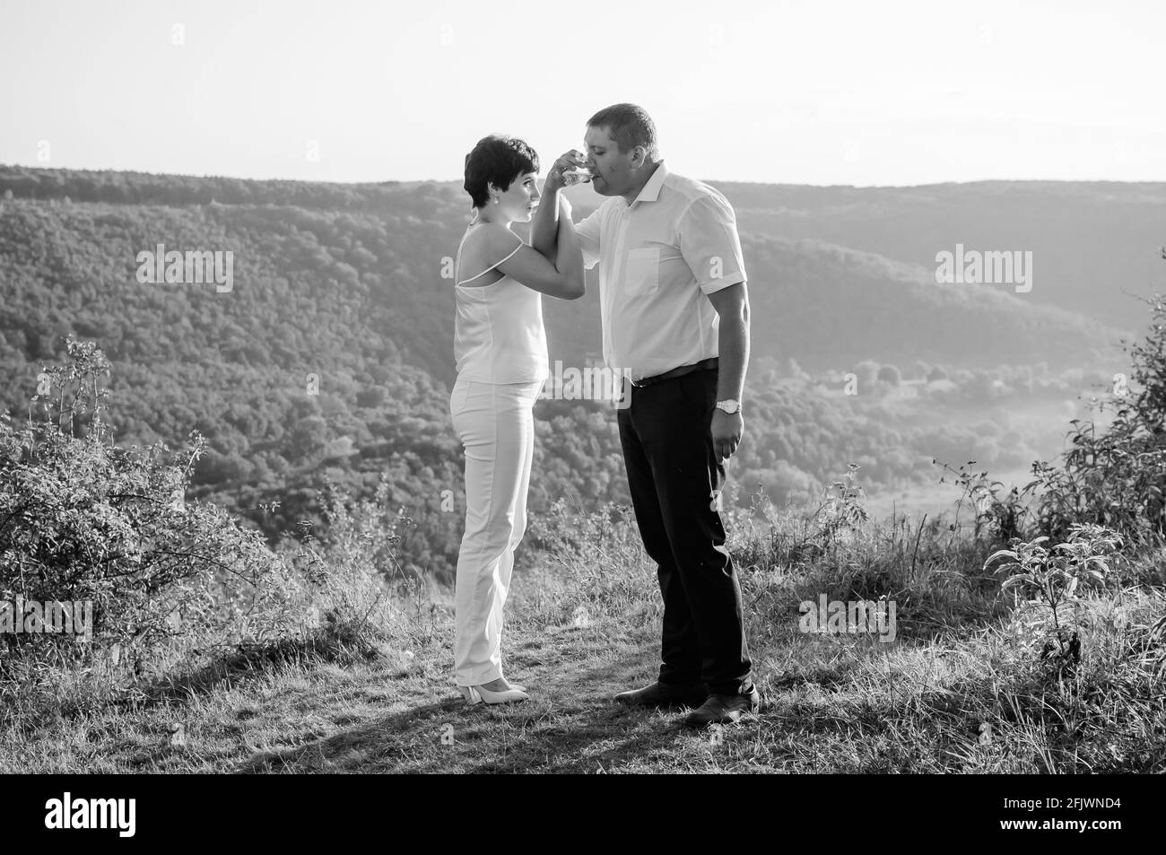 Mann und Frau gießen in Gläser und trinken Sekt Auf Waldgrund Stockfoto