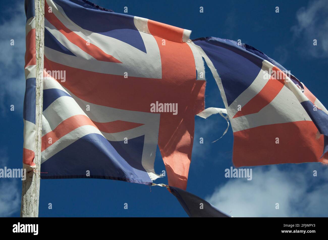 Alt und verblasst. Die Unionsflagge des Vereinigten Königreichs zerflattert und zerrissen, flattert und flattert im Wind gegen den Himmel. England, Großbritannien, Großbritannien. Stockfoto