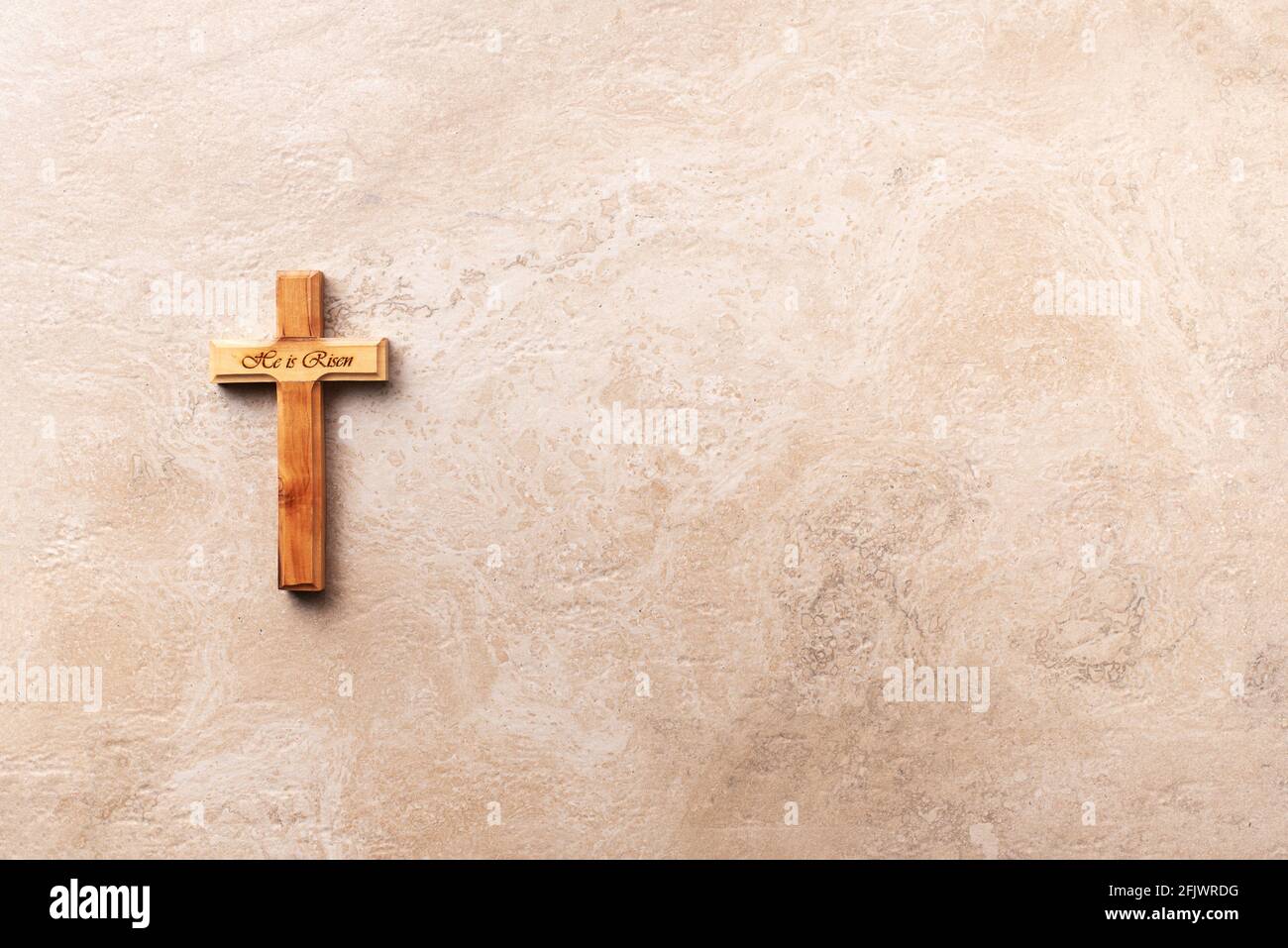 Holzkreuz mit Text Er ist auf Marmor Hintergrund gestiegen. Erinnerung an das Opfer Jesu und die Auferstehung Christi. Osterpassah. palmsonntag, gut Stockfoto