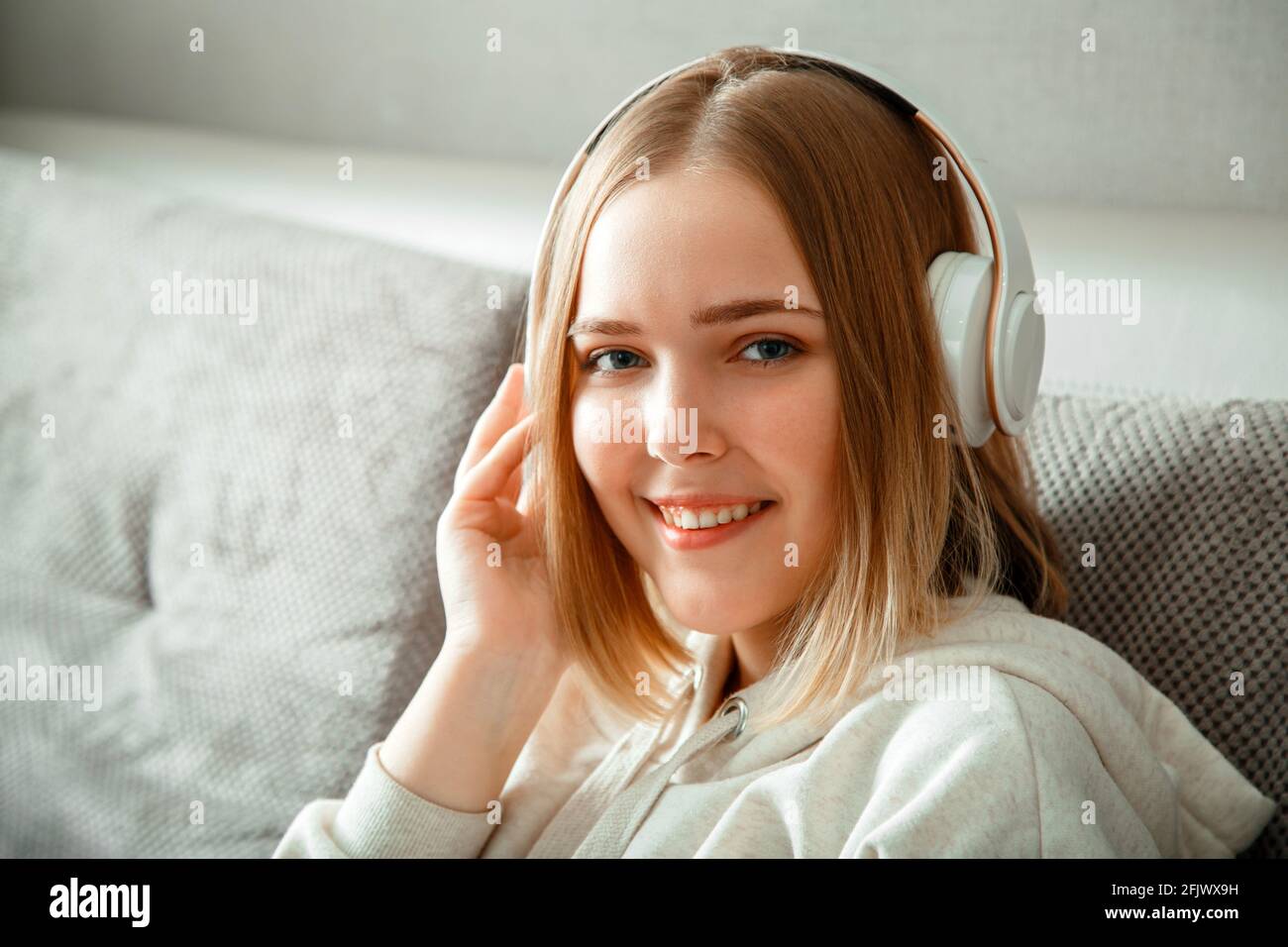 Glückliche junge Frau, die auf dem Sofa sitzt und Kopfhörer hat. Frau oder Teenager-Mädchen ruhen, Glückseligkeit genießen Sie Musik auf der Couch zu Hause Interieur des Lebens hören Stockfoto