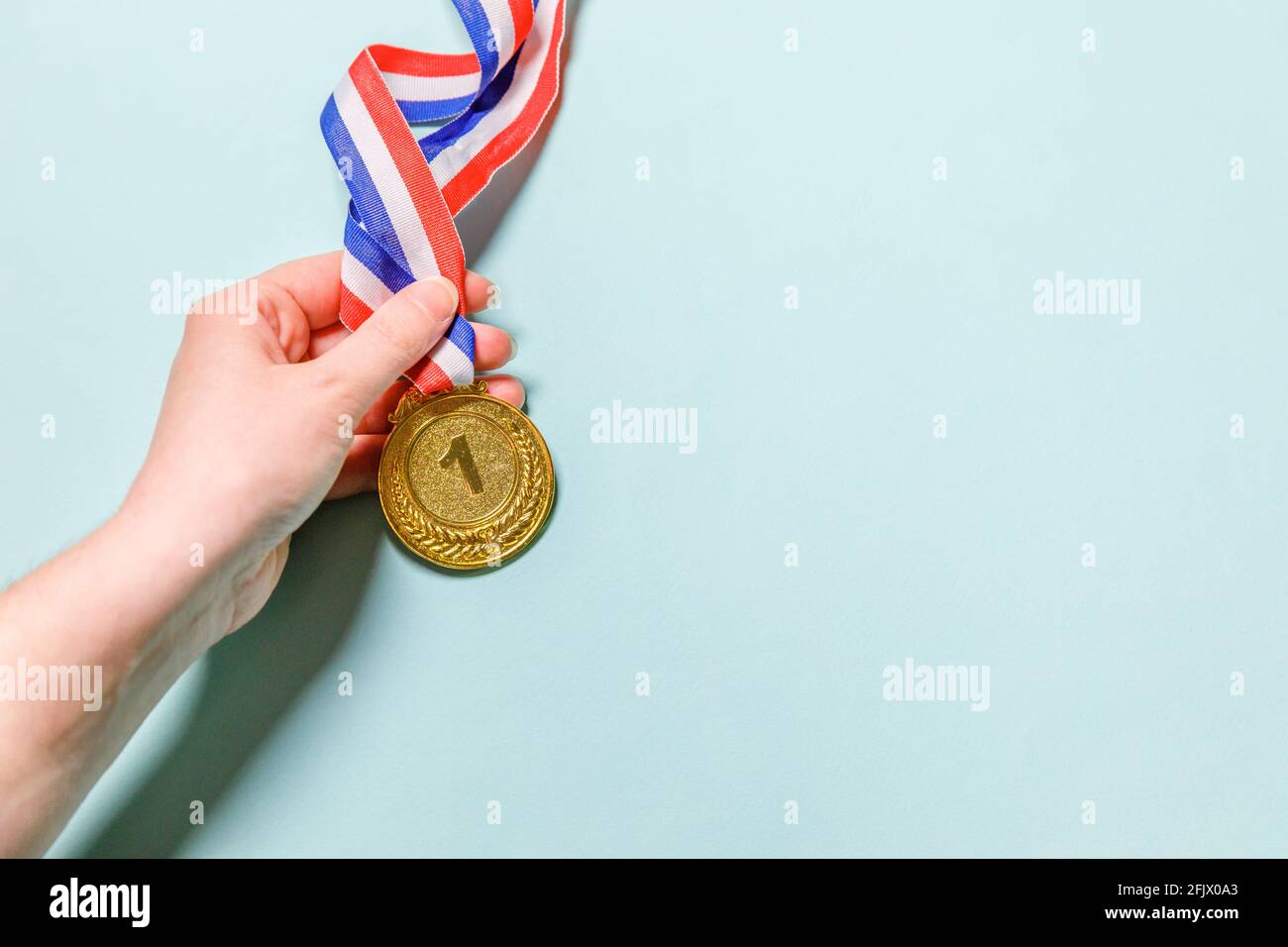 Einfach flach Lay Design Hand halten Gewinner oder Champion Gold Trophäe Medaille isoliert auf blau bunten Hintergrund. Sieg erster Platz des Wettbewerbs Stockfoto