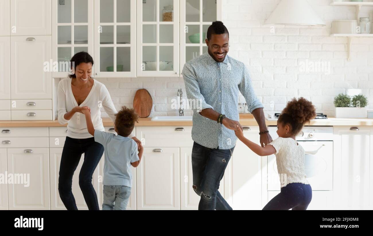 Glückliche afroamerikanische Eltern und zwei Kinder tanzen zu Musik Stockfoto