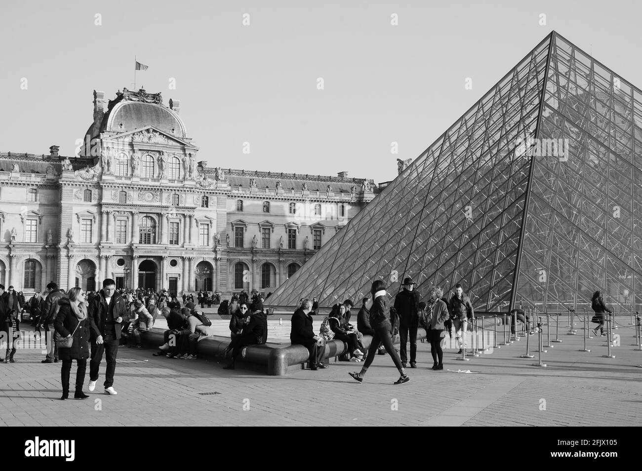 Touristen in der Nähe der Pyramide des Louvre bei Sonnenuntergang. Der Louvre ist das am meisten besuchte Museum der Welt und empfängt jährlich mehr als 9 Millionen Besucher. Schwarz-weiß Stockfoto