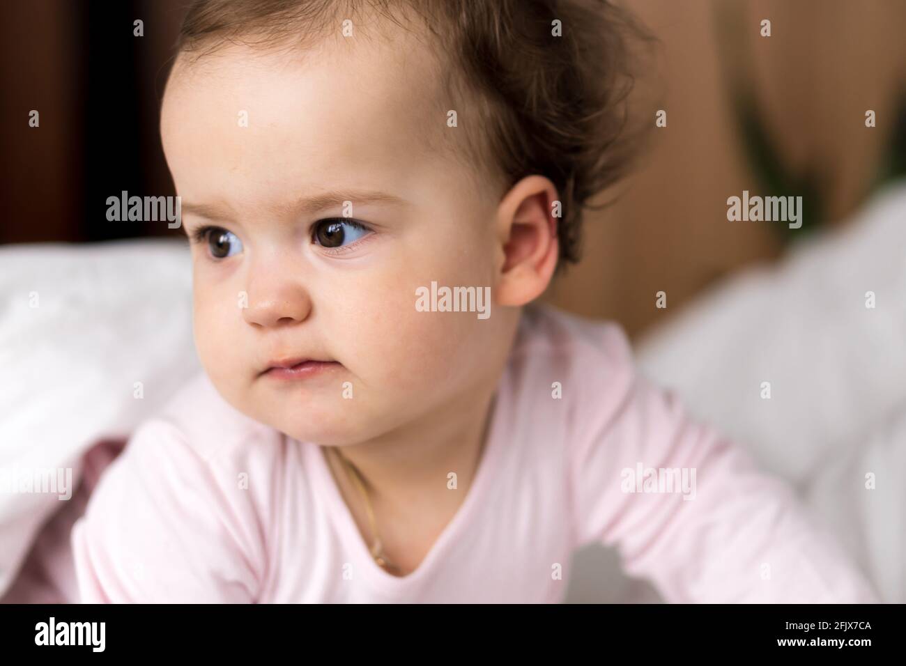 Authentische Porträt niedlich kaukasischen kleinen Säugling mollig Baby Mädchen oder Jungen in rosa schlafend beim Aufwachen Blick auf die Kamera im weißen Bett. Kinderbetreuung Stockfoto