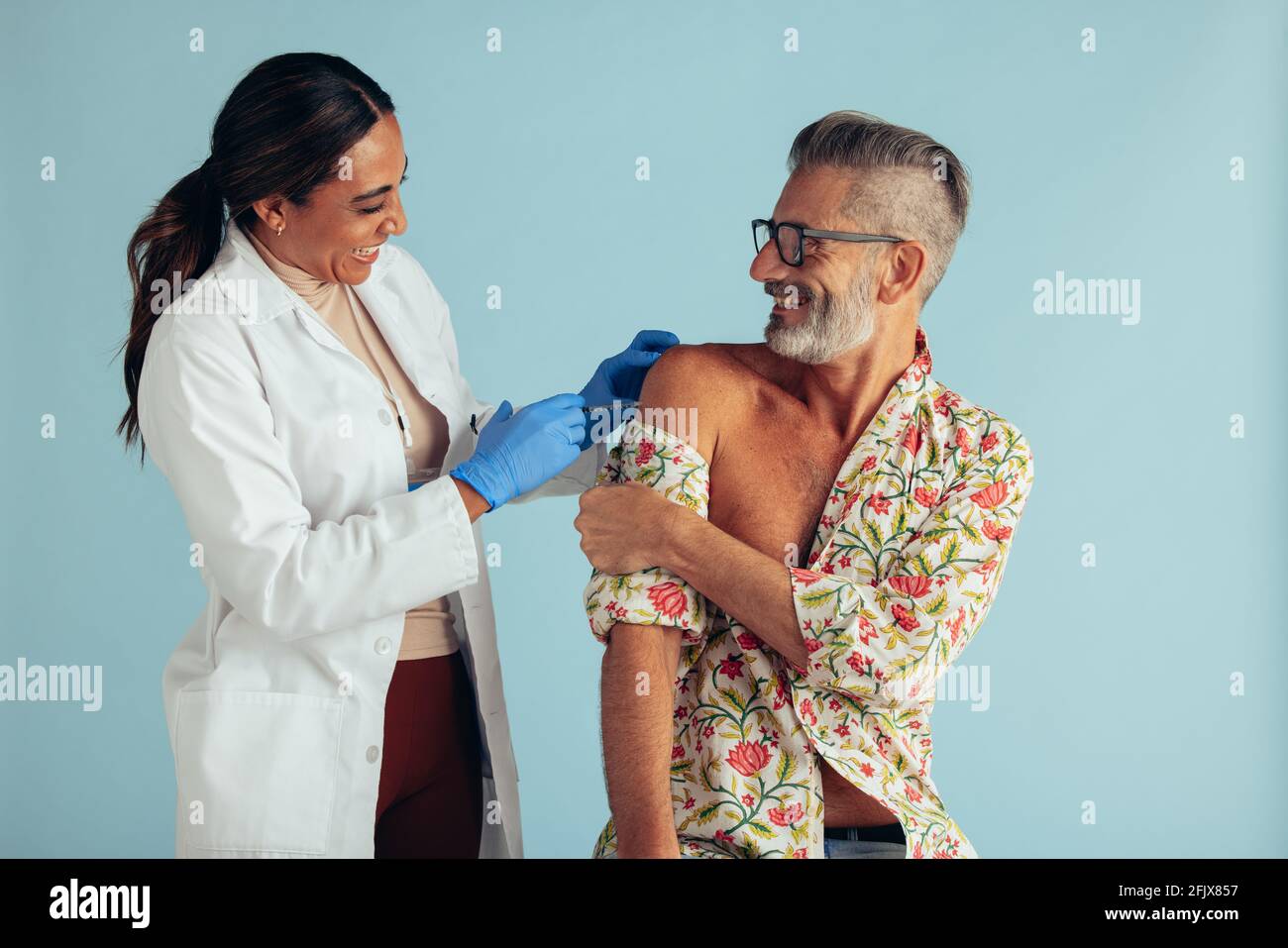 Lächelnder Mann, der von einer Ärztin eine Grippeimpfung erhalten hat. Medizinische Fachkraft, die mittleren erwachsenen Mann impft. Stockfoto