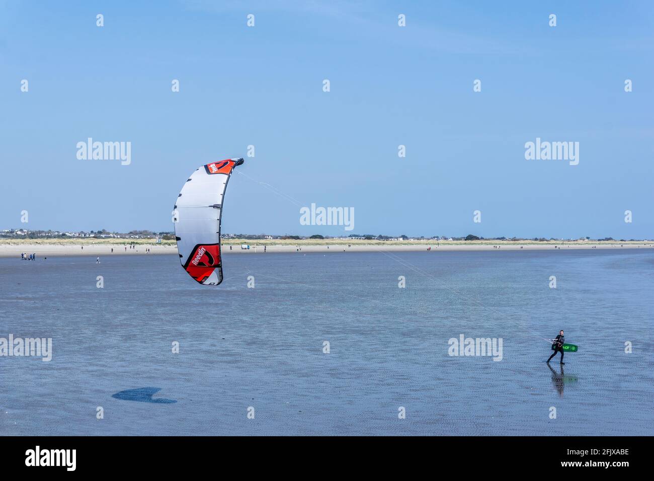 Kitesurfen. Ein eineineinmunter Kite-Surfer am Dollymount Strand in Dublin, Irland, der sich in Richtung Wasser bewegt. Stockfoto