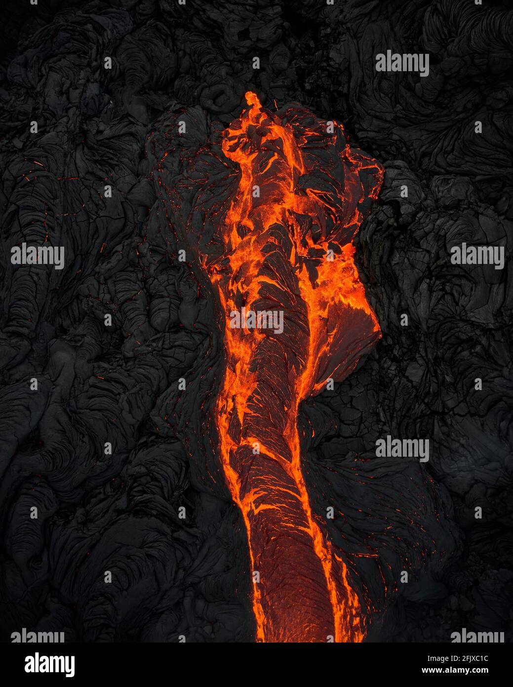 Vulkanisches Gelände mit orange fließendem Magma Stockfoto