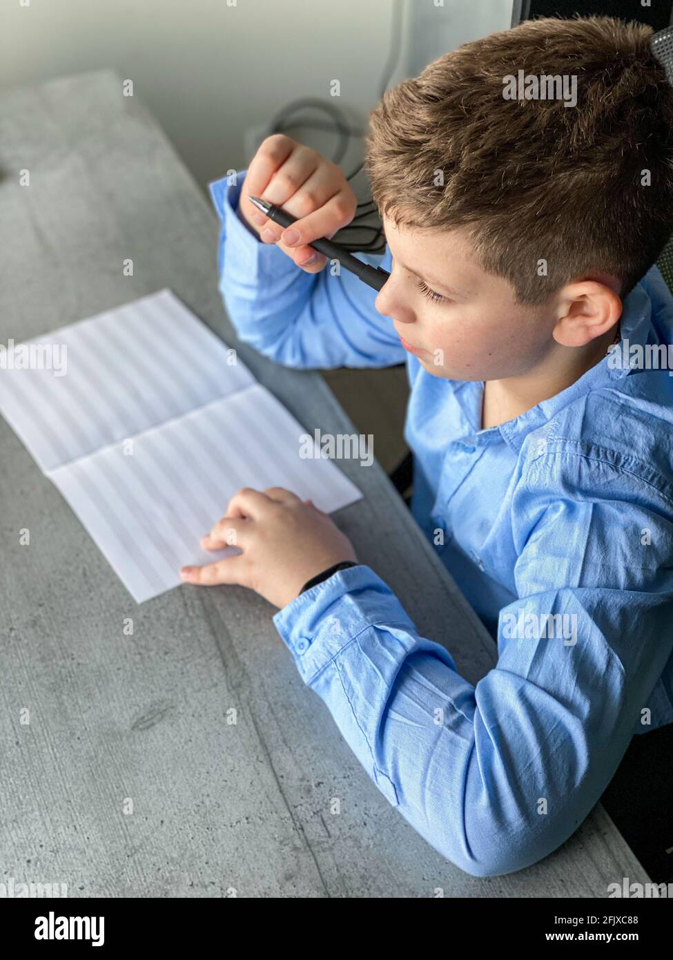 Junge in einem blauen Hemd schaut aus dem Fenster Stockfoto
