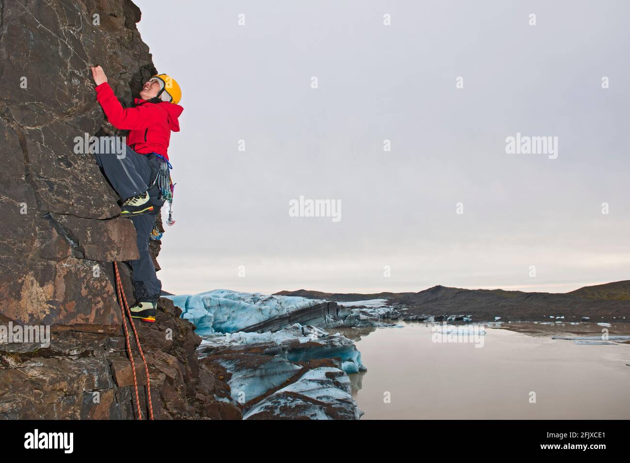 Weibliche Kletterin bestiegt die Felswand in Skaftafell / Island Stockfoto