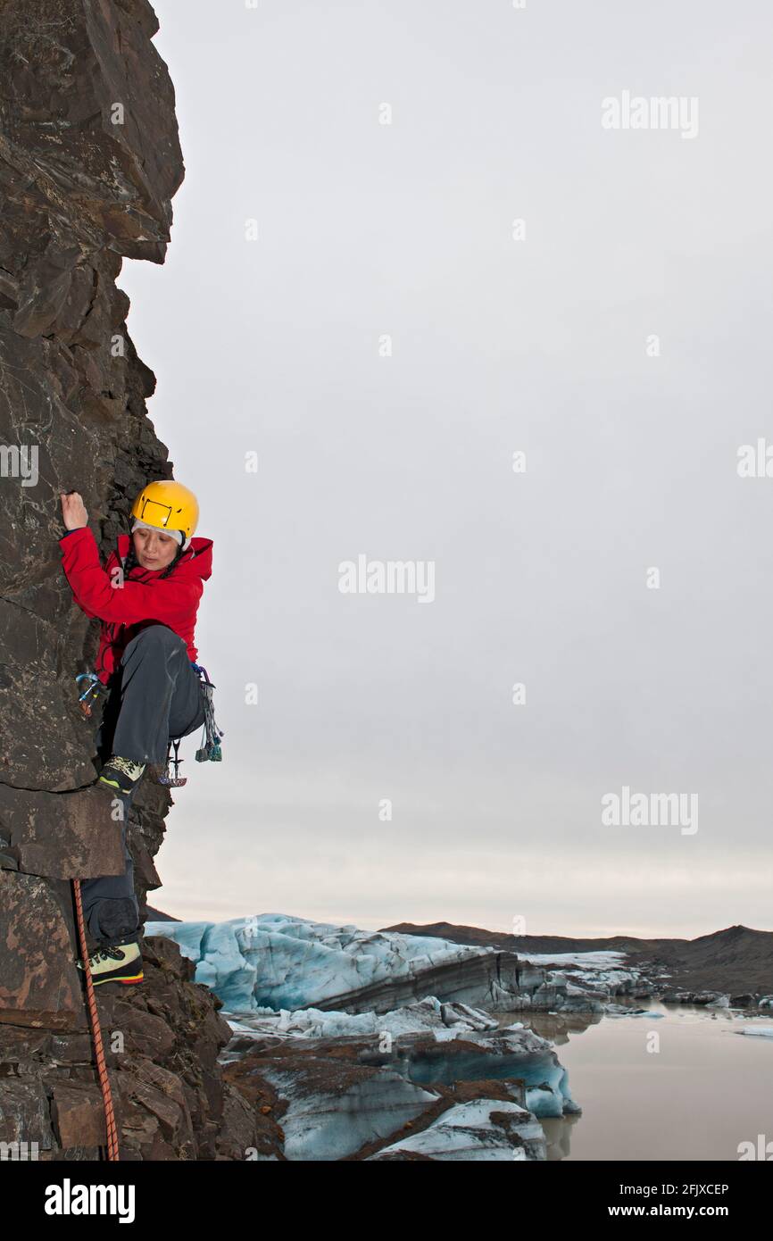 Weibliche Kletterin bestiegt die Felswand in Skaftafell / Island Stockfoto