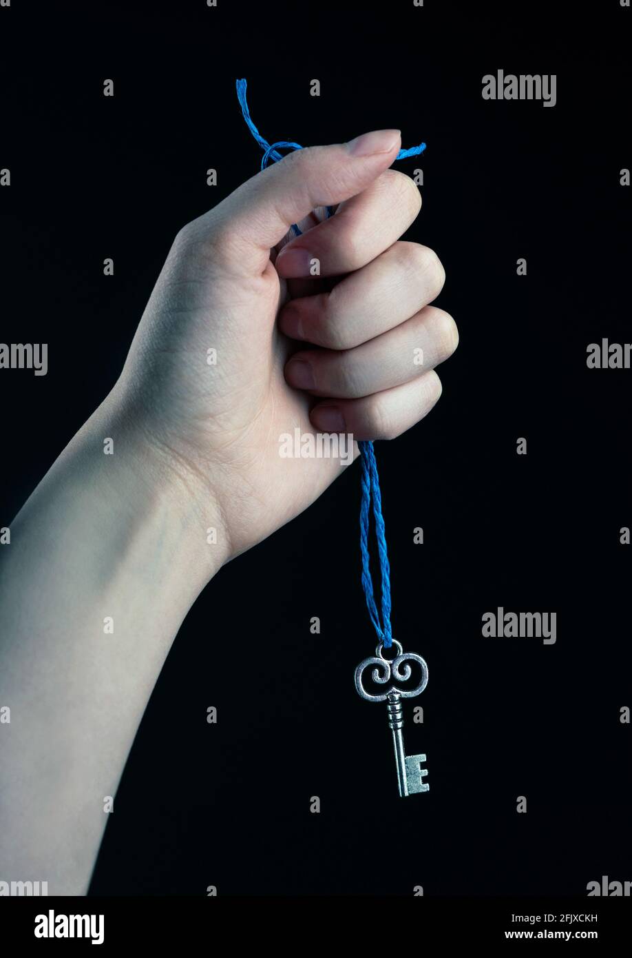 Hand hält blaue Schnur mit silbernem Schlüssel angebracht Stockfoto