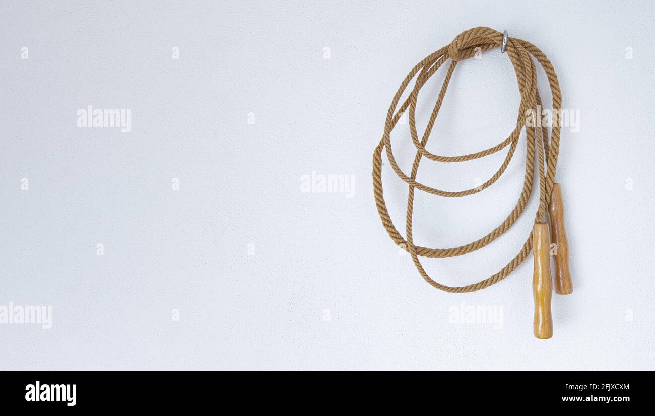 Ein altes Springseil, das an einer weißen Wand hängt. Stockfoto