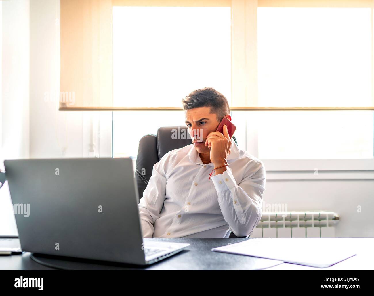 der manager nimmt einen Anruf an, während er von seinem Computer aus an arbeitet Zu Hause Stockfoto