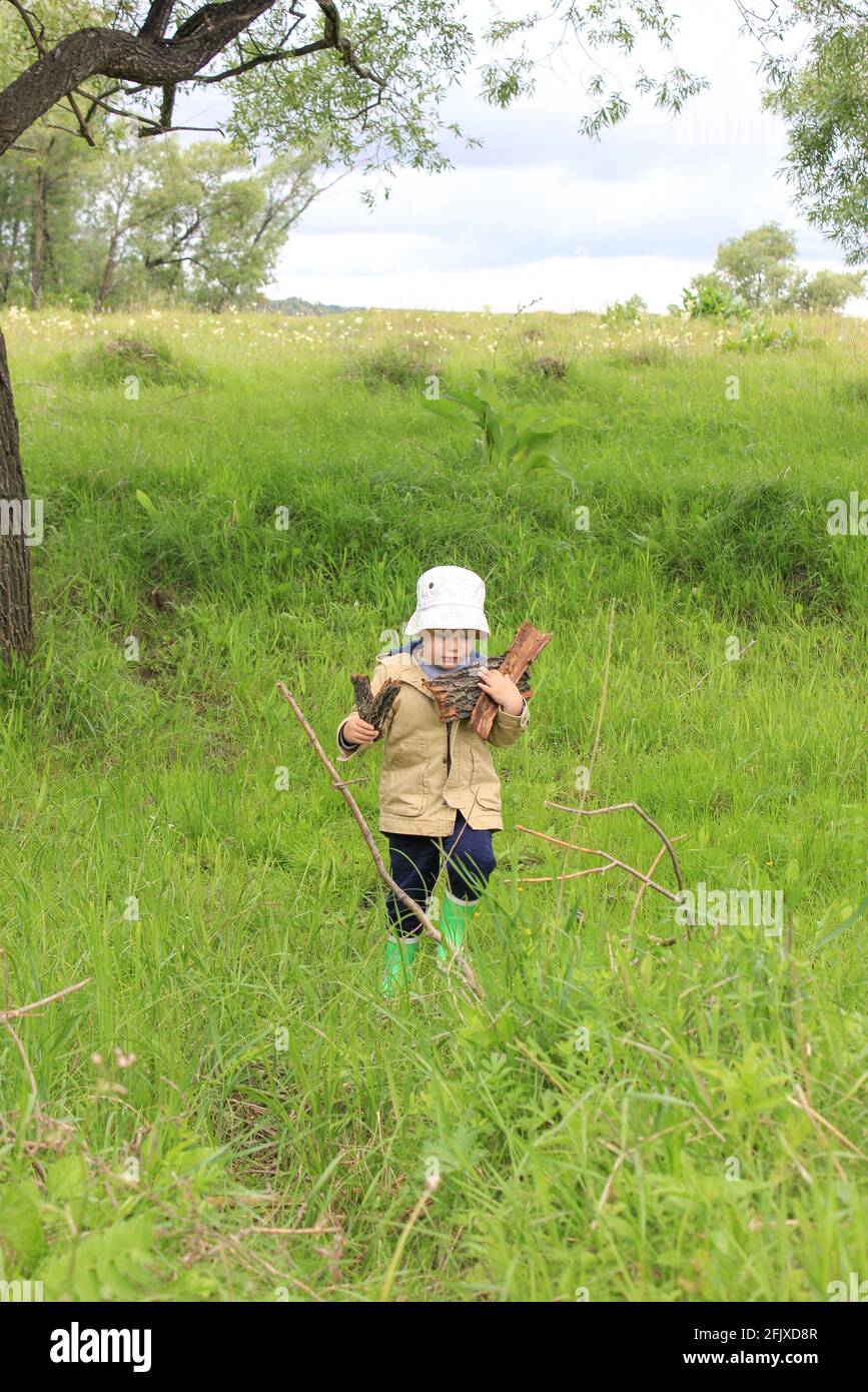 Ein 3-jähriges Kind spaziert auf einer grünen Wiese Stockfoto