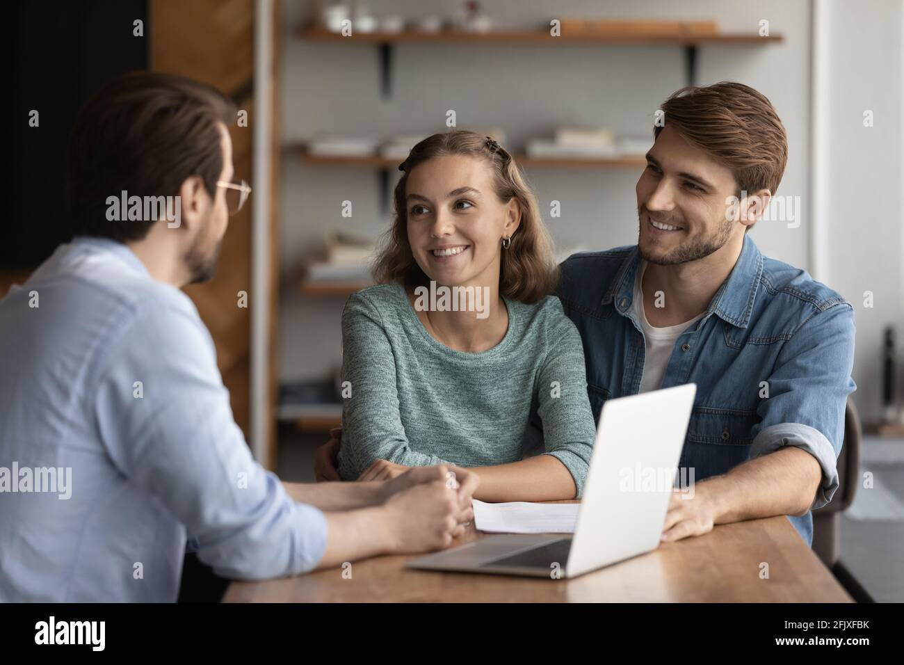 Lächelndes kaukasisches Paar trifft sich mit dem makler im Büro Stockfoto